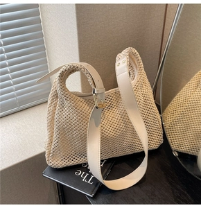 Close-up of woven straw handbag texture with adjustable leather shoulder strap and gold buckle