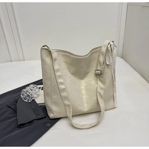 Detail of cream white textured leather bucket bag with elegant lace ribbon decoration