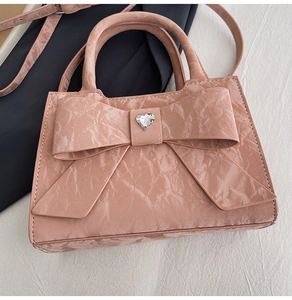 Detail of pink bow handbag with heart rhinestone and wrinkled glossy texture