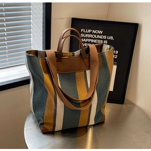 Detail of color-block striped canvas tote with leather handles and long shoulder strap