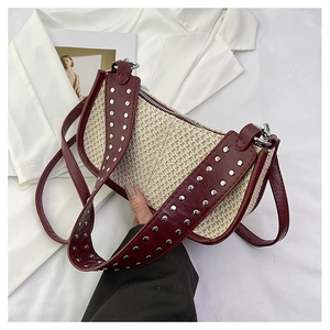 Détail du sac en paille tressée avec lanières en cuir bordeaux et rivets argentés