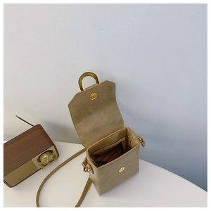 Detail view of khaki mini crossbody bag with golden metal handle and striped inner lining