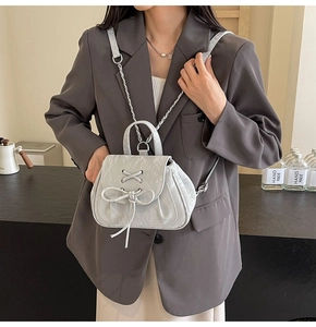 Dettaglio dello zaino grigio chiaro stile ballerina con fiocco, lacci e catena metallica