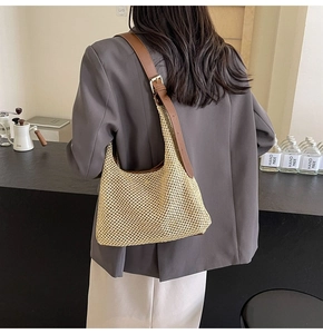 Detailed view of adjustable leather strap and beige woven texture on beach shoulder bag