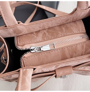 Close-up of pink tote bag showing silver metal zipper and wrinkled texture detail