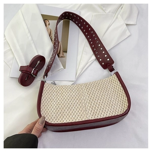 Détail du sac tressé avec des rivets argentés sur une large bandoulière en cuir rouge foncé