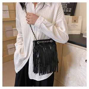 Détail d'un sac à franges en cuir noir avec bandoulière chaîne dorée en décor moderne