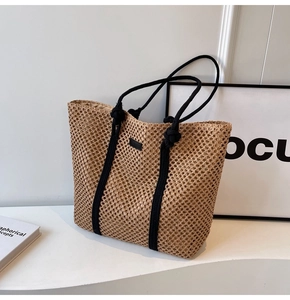 Close-up of hollow woven straw tote bag with black rope handles for summer beach vacations
