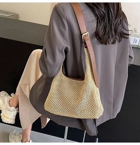 Detail of hand-woven beige mesh bag featuring adjustable brown leather strap and gold buckle