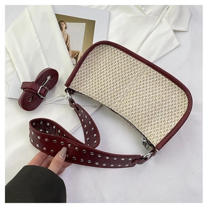 Détail du sac croissant en paille tressée avec bordure en cuir bordeaux et clous argentés