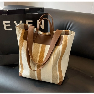 Detail of the striped canvas tote bag showing the leather handles and woven texture