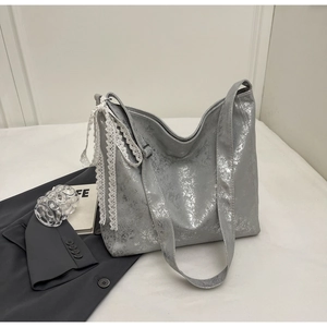 Detail of silver metallic tote bag with lace bow and adjustable shoulder strap