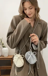 Detail of mini leather bags with bows and tassels in cream and silver-grey colors