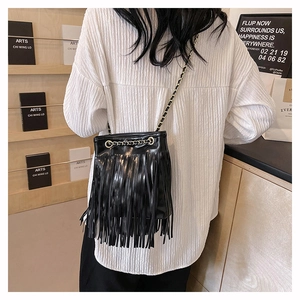 Détail d'un sac seau en cuir noir orné de longues franges et d'une bandoulière chaîne