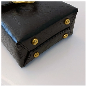 Detail of black embossed leather handbag base with gold protective metal rivets