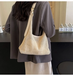 Detail view of woven hollow shoulder bag with adjustable leather strap worn by a model