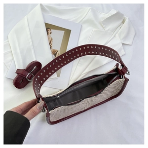 Vue détaillée du sac en paille tressée avec bordure en cuir rouge et rivets