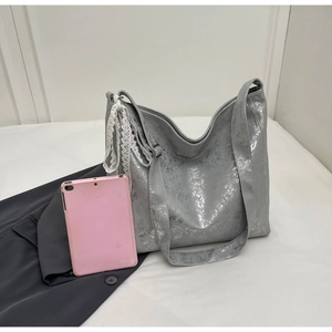 Silver bucket bag detail showing large capacity with lace ribbon and a tablet for scale