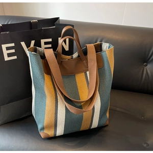 Detailed view of color block striped canvas tote bag with leather reinforced corners and strap