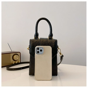 Close-up of black mini crossbody bag with vintage texture and gold hardware details