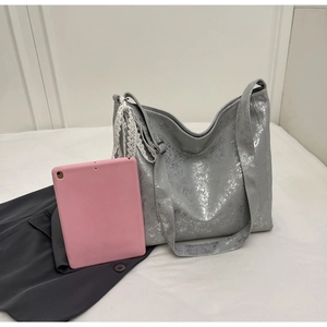 Macro shot of silver metallic bucket bag showing lace strap detail and large capacity