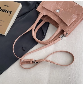Detail of a pink wrinkled leather handbag with a large bow and heart rhinestone detail