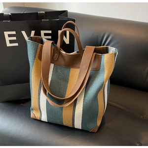 Close-up of color-block striped canvas tote bag with brown leather handles and straps