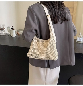 Detail of minimalist cream woven shoulder bag with adjustable white leather strap and metal buckle