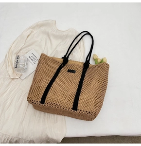 Detail shot of the woven texture and black rope handle on a straw tote beach bag