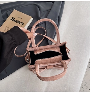Detailed top view of pink embossed crossbody bag with interior zipper pocket and strap