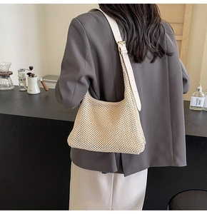 Detail of the woven hollow design on beige straw bag with adjustable leather strap