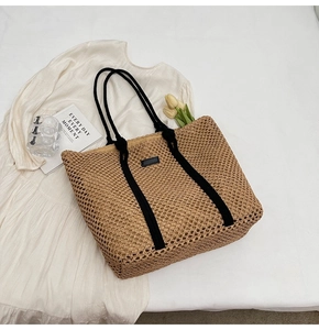 Detail of hollow woven tote bag with brown mesh texture and black rope handles