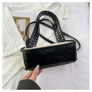 Détail du sac croissant tissé avec bordure en cuir noir et rivets sur la poignée