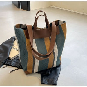 Macro detail of tricolor woven canvas texture and premium brown leather handle on tote bag