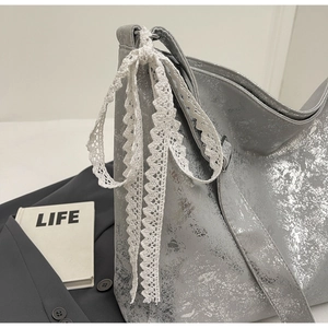 Detailed macro view of metallic foil texture and white lace bow on the silver bucket bag