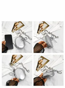 Detail of silver mini chain bag with bow decoration and size comparison to phone
