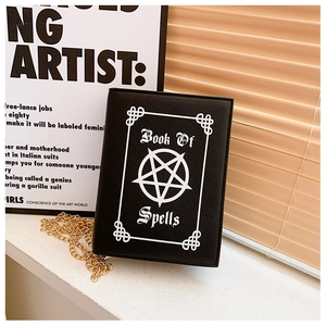 Macro detail of gothic book-shaped crossbody bag with silver star and book of spells print
