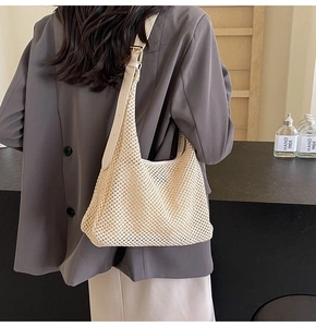 Detail of off-white hollow woven hobo bag with leather strap and golden metal buckle