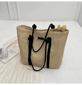 Close-up detail of beige hollow woven straw tote bag with black rope handles and inner lining