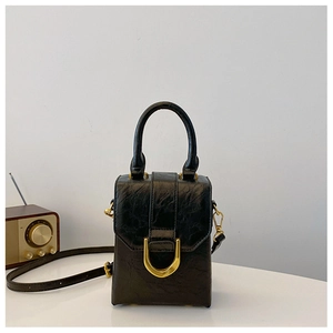 Detail of a vintage-style black pleated square bag with a gold D-ring buckle