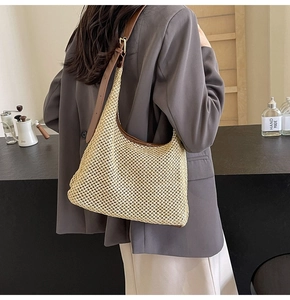 Detail view of hollow woven shoulder bag with leather straps and metal buckle