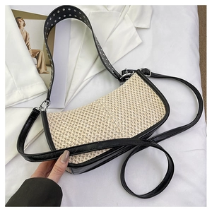 Détail d'un sac en paille tressée beige avec bandoulière à rivets et boucles