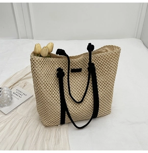 Close-up of hollow woven tote bag with contrast black handles and texture detail