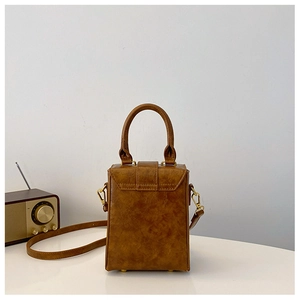 Detail view of a vintage brown leather mini box bag with gold-tone hardware on white backdrop