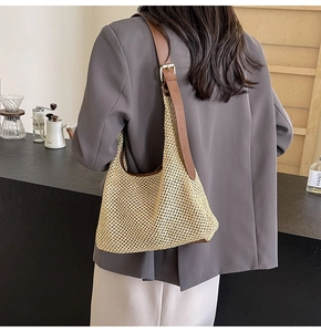 Detail of woven straw shoulder bag with leather strap and metal buckle on female model