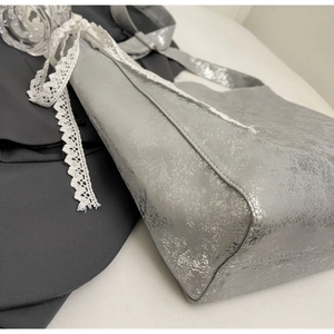 Detail of silver crackle texture bucket bag featuring white lace ribbon on the side seam