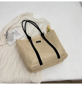 Detail shot of hollow woven tote bag with black handles and elegant leather patch