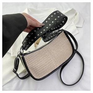 Détails du sac tressé avec rivets argentés sur la large bandoulière noire