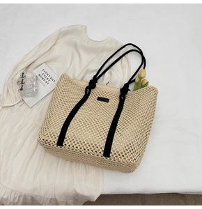 Detail shot of hollow woven straw tote with black straps and daily essentials