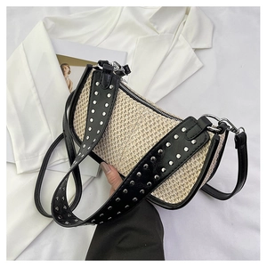 Détail d'un sac hobo tissé avec rivets argentés, bandoulière en cuir et zip métallique
